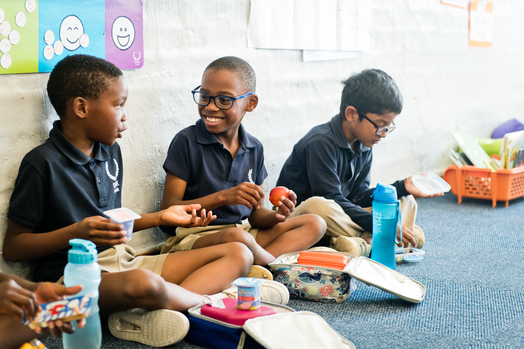 Three students at SPARK Schools having lunch together.