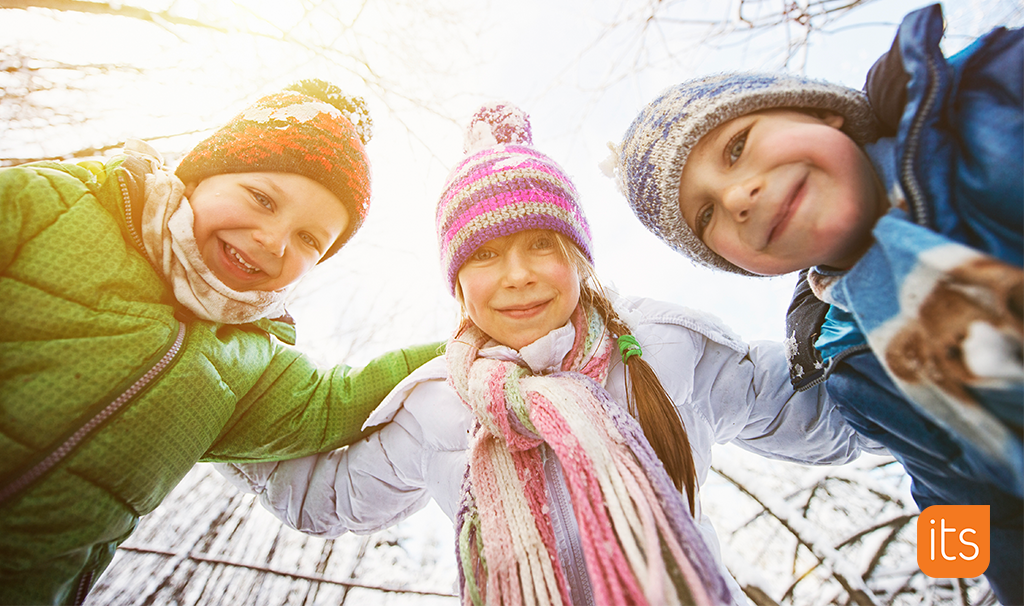 three children smiling, outside in the snow